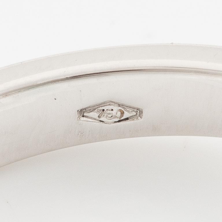 An 18K white gold ring set with an emerald-cut diamond and two step-cut emeralds.