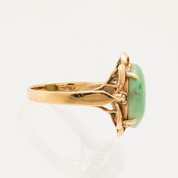 Ring in 14K gold with a green oval cabochon-cut stone and round brilliant-cut diamonds.