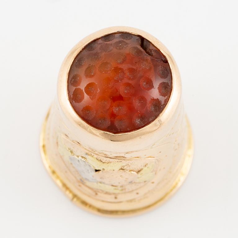 An 18K gold and carnelian thimble.