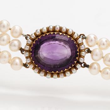 A three-strand cultured pearl collier with an amethyst and 14K gold.