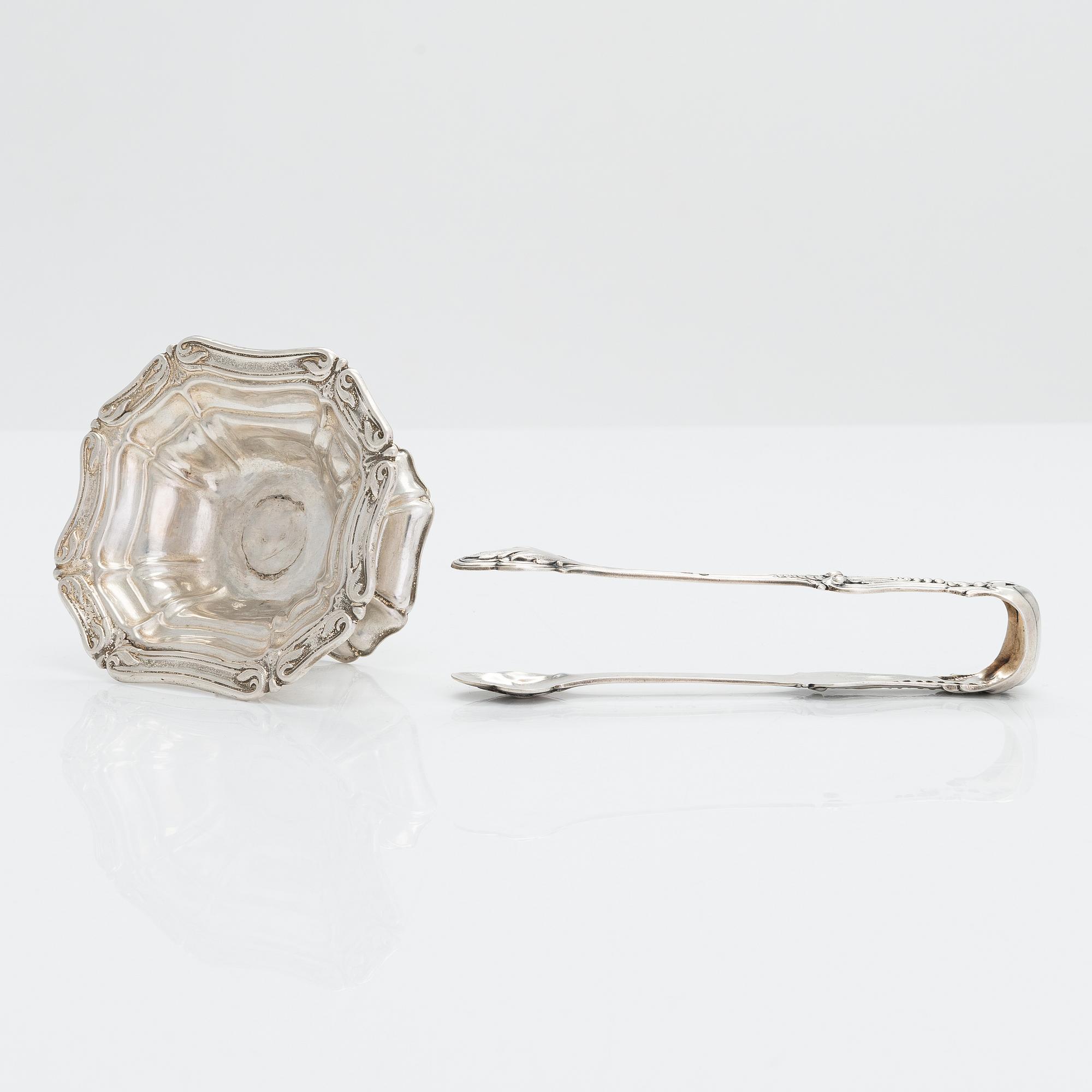 A silver sugar tong by Johan Warjus, and a silver salt cellar by Adolf Sper, St Petersburg 1856 and 1849.