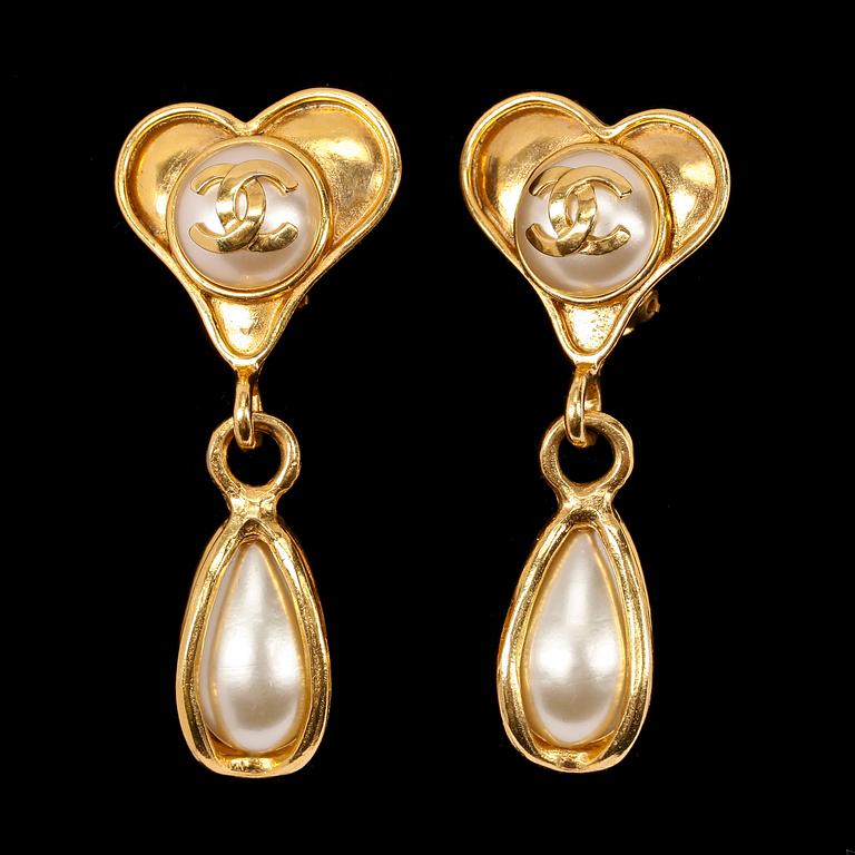 A pair of golden earclips with a decorative pearl by Chanel.