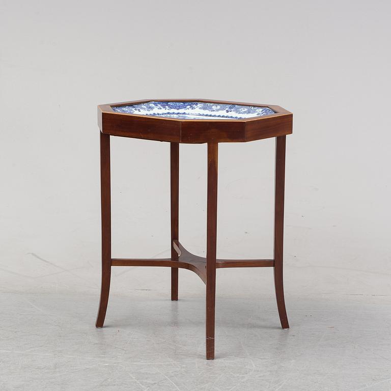 A mahogany veneered table with a Chinese blue and white porcelain charger, Qianlong (1736-95).