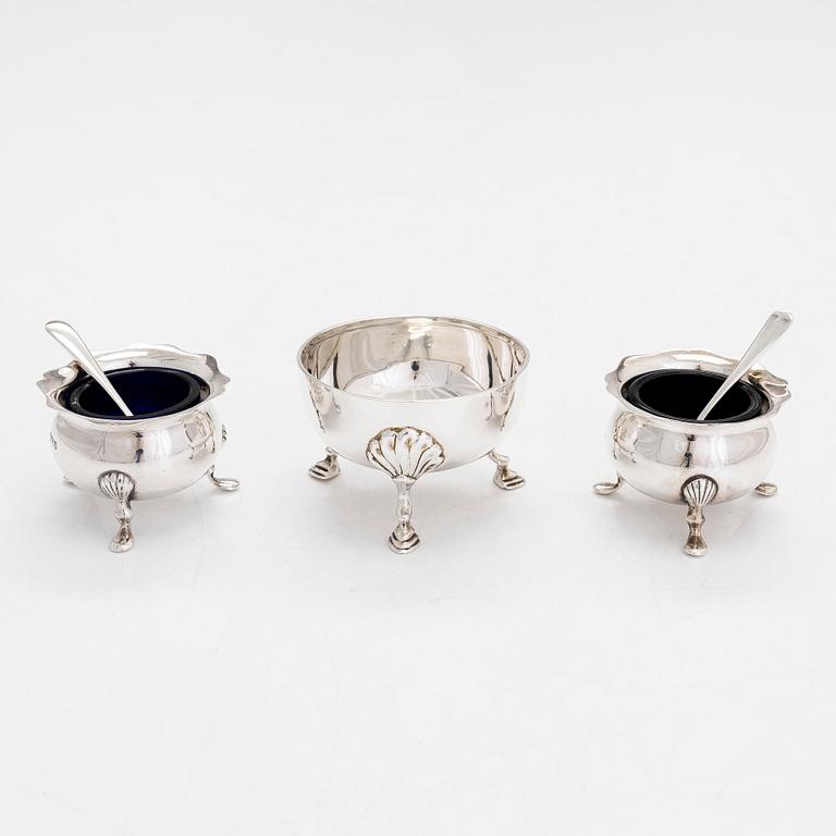 A pair of sterling silver salt cellars, two salt spoons, and a bowl, Sheffield 1898 and 1915, Birmingham 1923 and 1947.