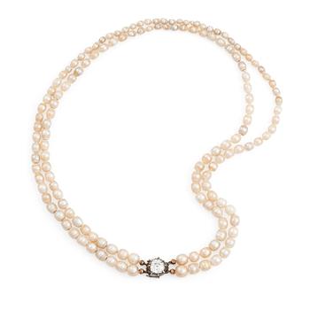 514. A two strand natural pearl necklace with a silver  clasp set with an old-cut diamond.