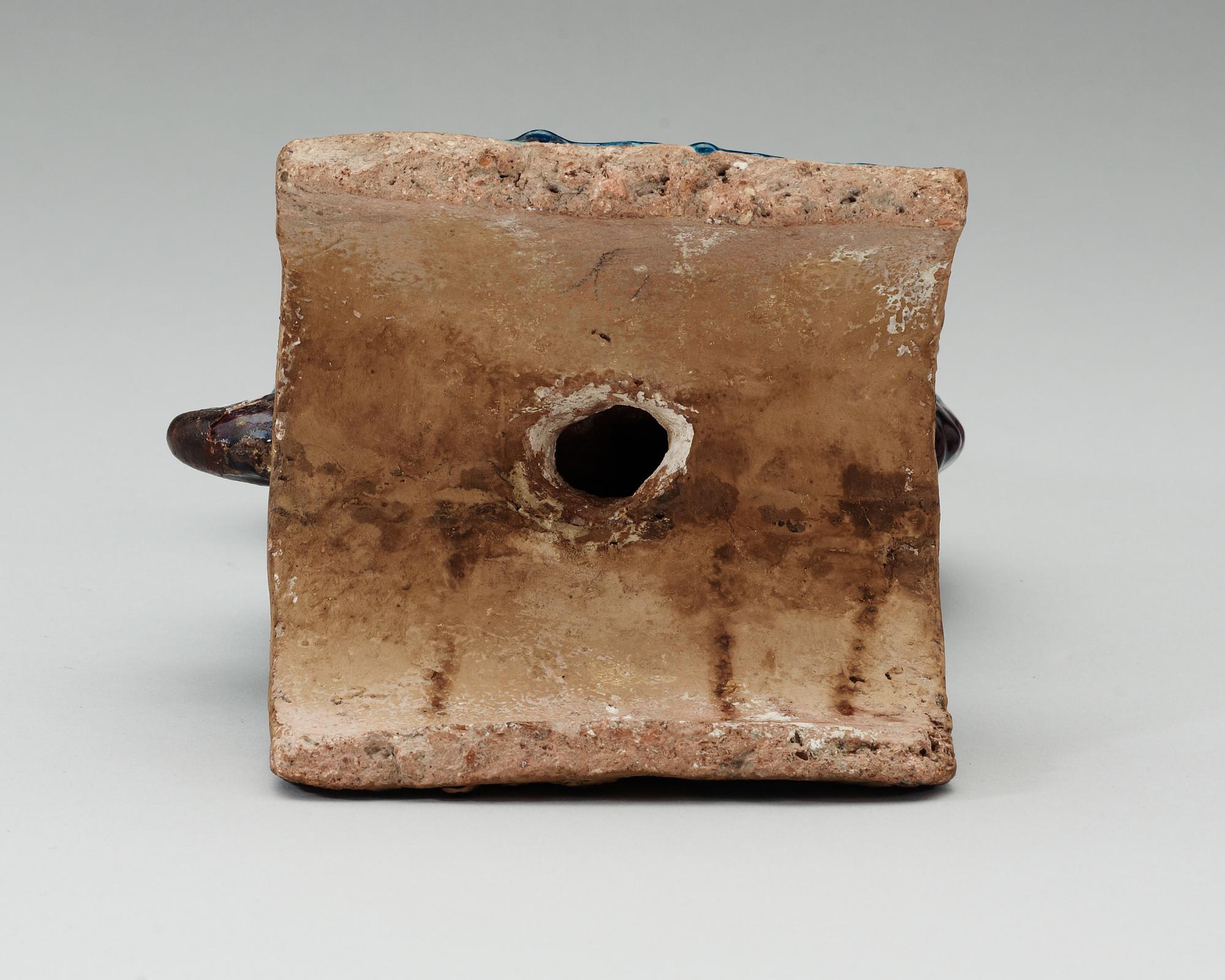 A turquoise and purple glazed roof top tile in the shape of a fish, Ming dynasty.