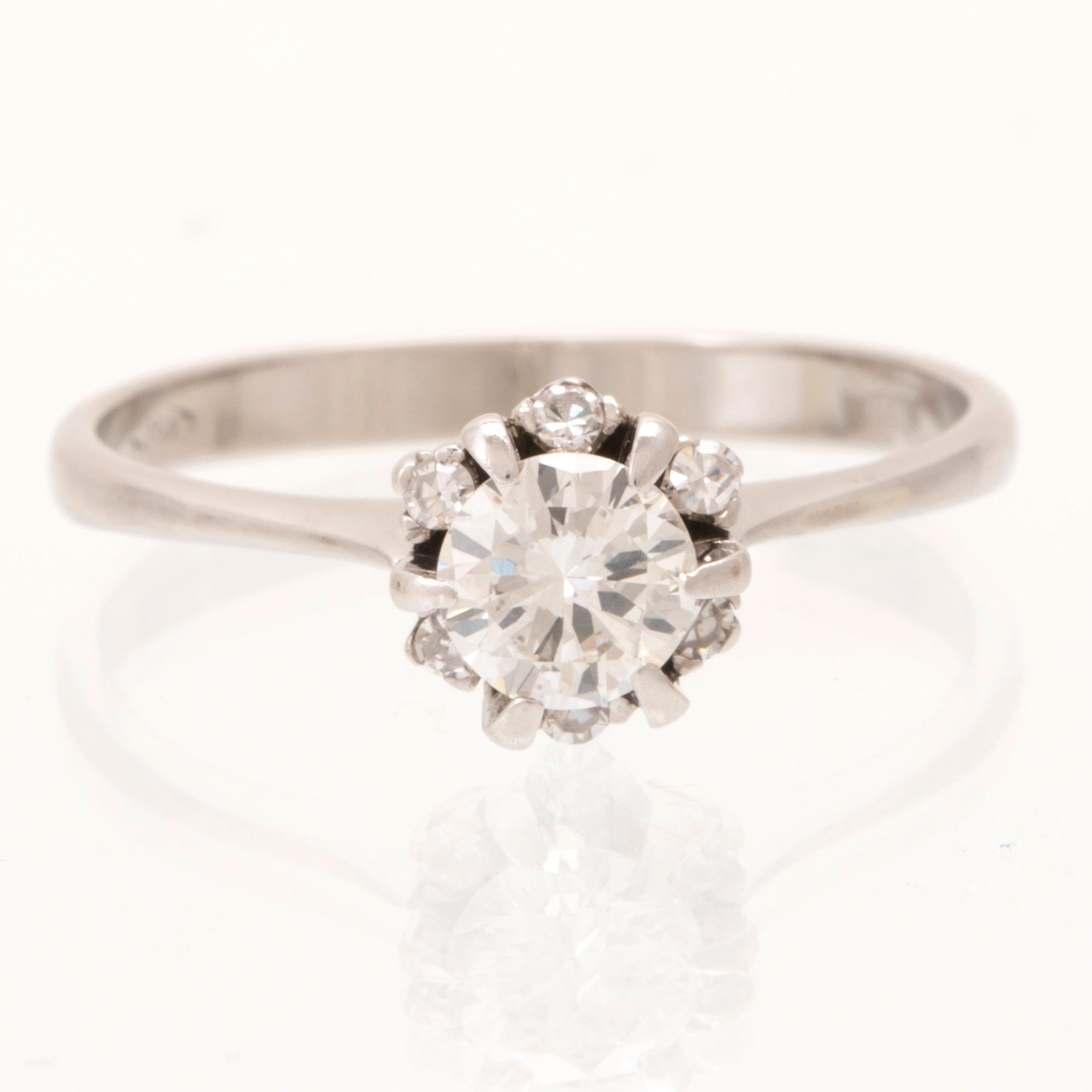 An 18K white gold ring set with a round brilliant cut diamond and single cut diamonds.