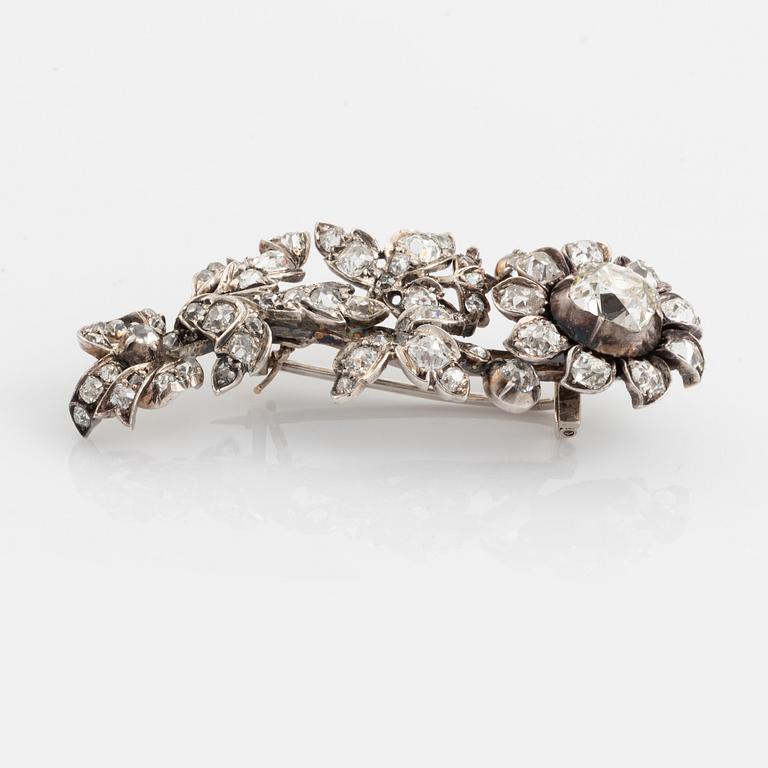 A flower silver brooch set with old-cut diamonds.