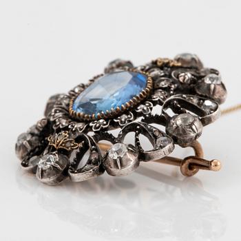 A 14K gold and silver brooch set with a synthetic sapphire and old- and rose-cut diamonds.