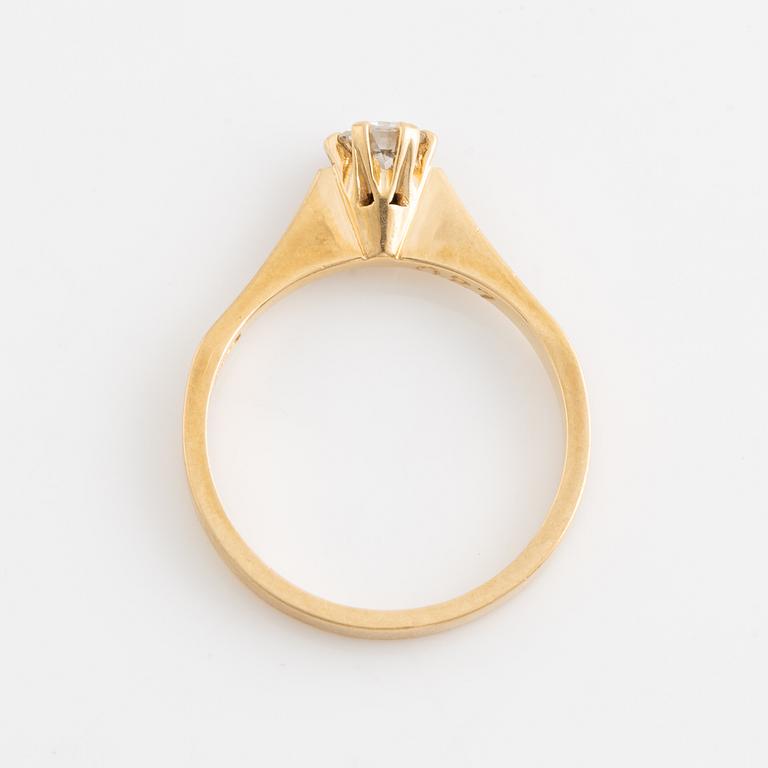 An 18K gold ring set with a round brilliant-cut diamond.