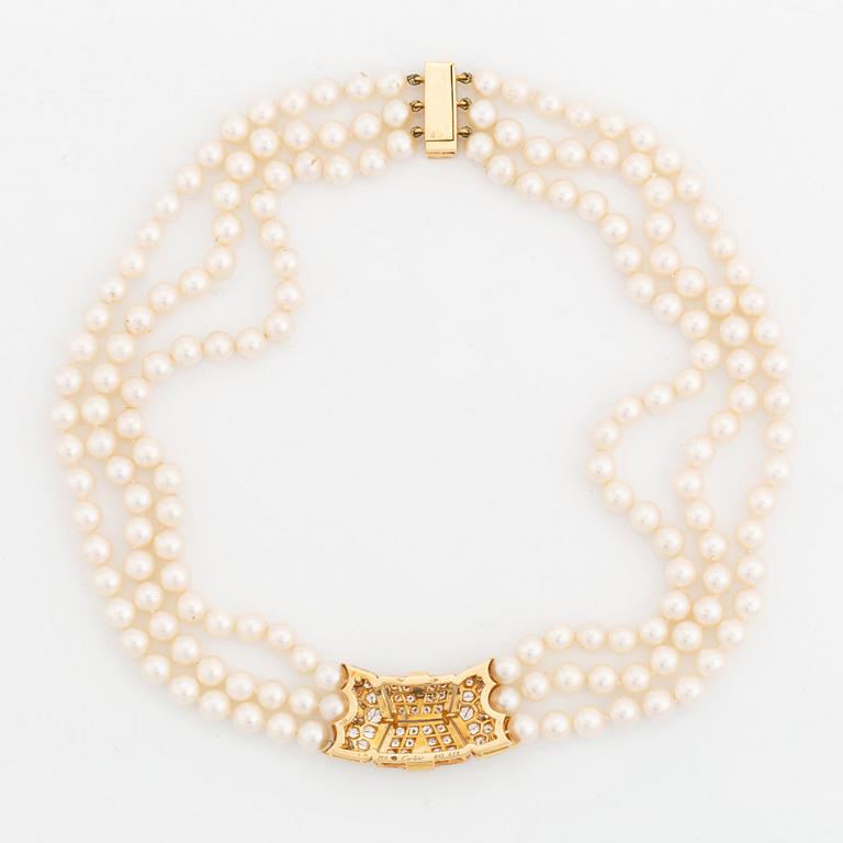 A Cartier triple strand cultured pearl necklace with an 18K gold clasp set with round brilliant-cut diamonds.