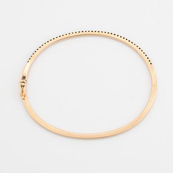 An 18K rose gold bangle set with round brilliant-cut black diamonds.