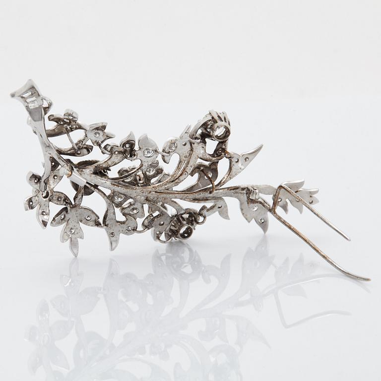 An 18K white gold brooch set with round brilliant-cut diamonds.