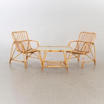 A pair of ratten mid 20th century armchairs and a lounge table.