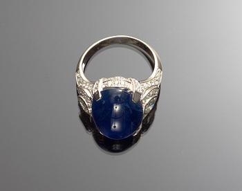 RING, cabochonslipad blå safir, 14.37 ct med briljantslipade diamanter, tot. ca 1.30 ct. Cert. GRS.