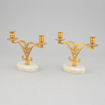 A pair of brass candle sticks om marble stands from the middle of 20th century.