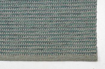 A "Dogtooth metallic green" carpet, Vandra rugs, c. 562 x 265 cm.