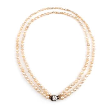 514. A two strand natural pearl necklace with a silver  clasp set with an old-cut diamond.