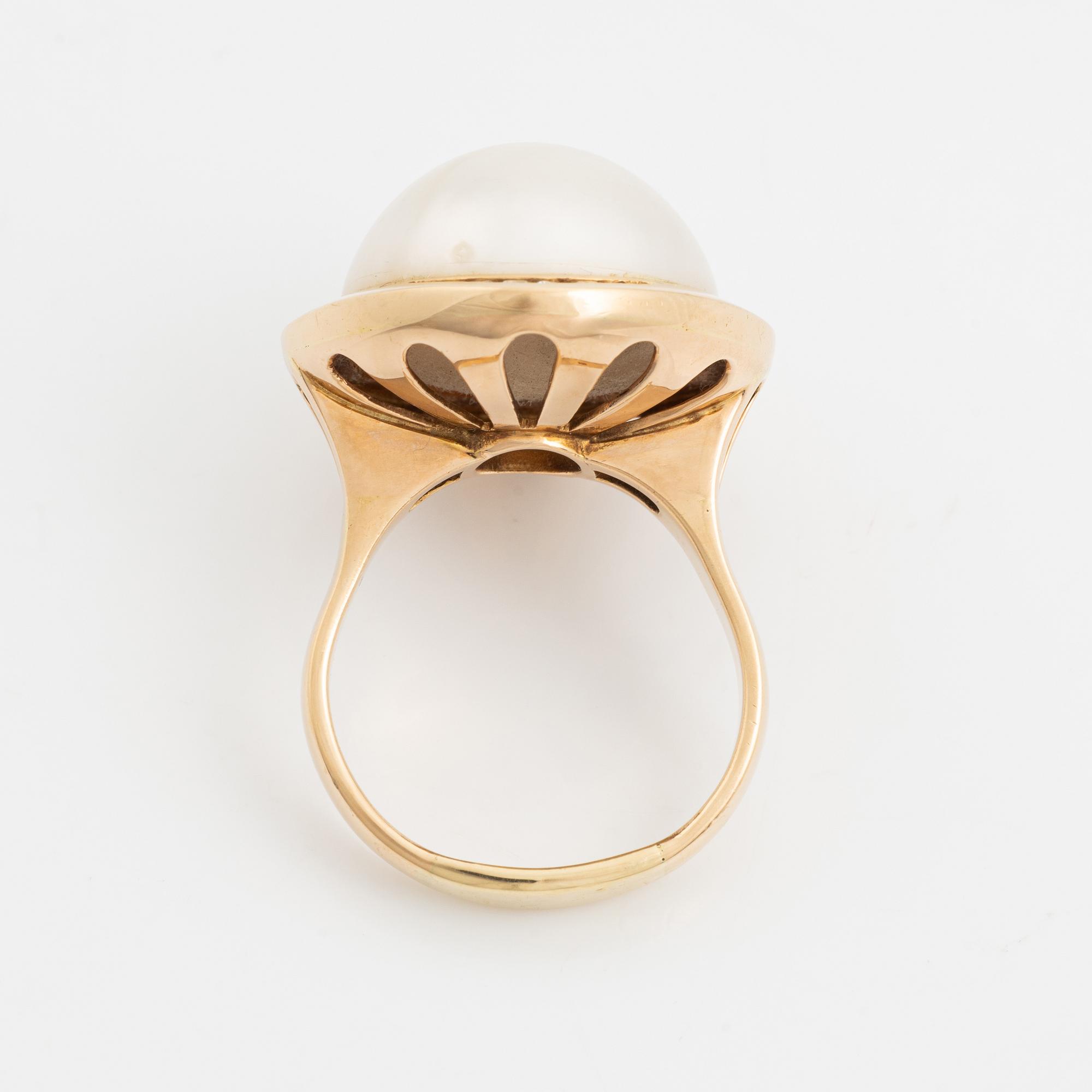 A 14 k gold ring set with a half pearl and round brilliant-cut diamonds.