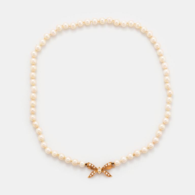 A cultured pearl necklace with a bow clasp in 18K gold set with round brilliant-cut diamonds.