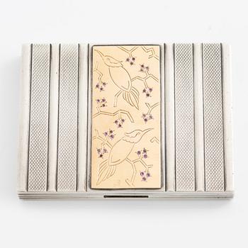 Puderdosa, silver samt guld. Med dekor av fåglar och rosa stenar.