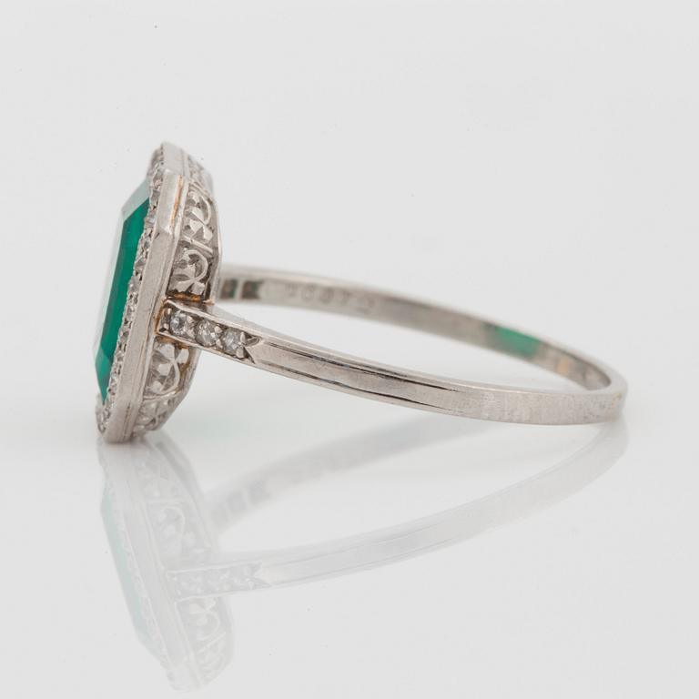 A platinum ring set with a Colombian step-cut emerald and old-cut diamonds in a fitted case from Cartier.