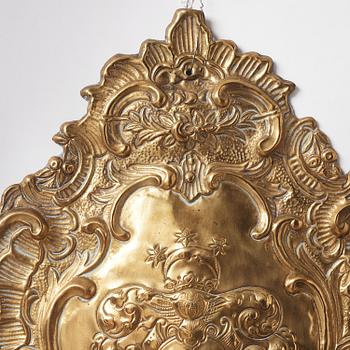 A pair of North European Rococo two-branch repoussé brass reflector plates, mid 18th century.