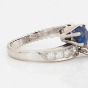 A CROSS-OVER RING set with a round mixed-cut sapphire and round brilliant-cut diamonds.