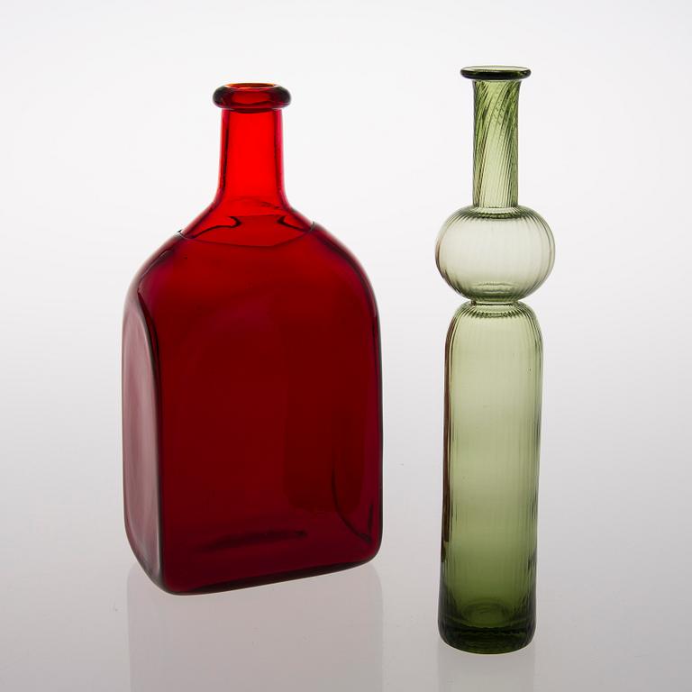 Two glass bottles. A green 'Neptuna' bottle designed by Nanny Still in 1964 and a red bottle from Riihimäen Lasi oy.