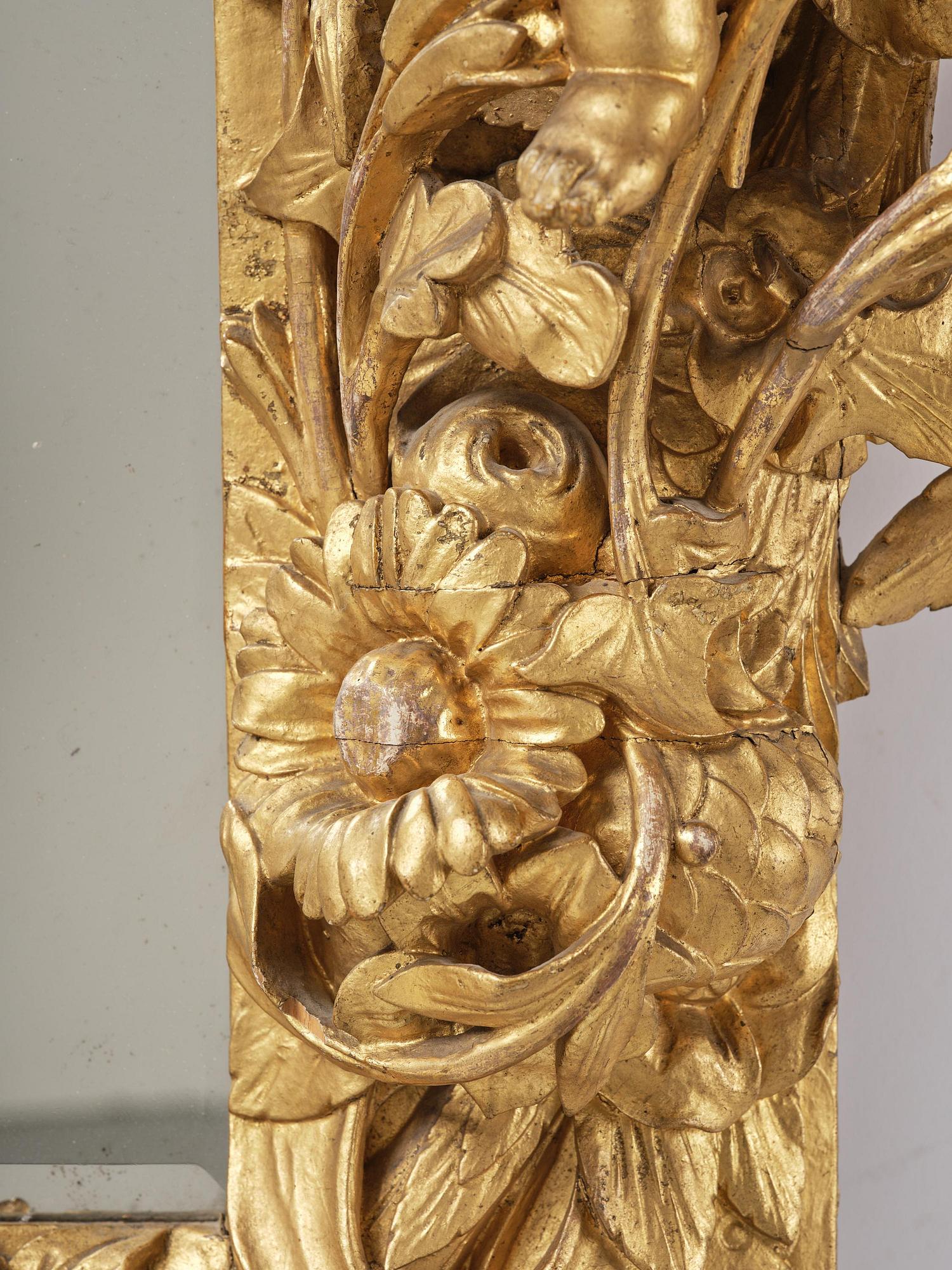 A presumably Dutch Louis XIV carved giltwood frame with mirror glass, in the style of Jean Le Pautre, late 17th century.