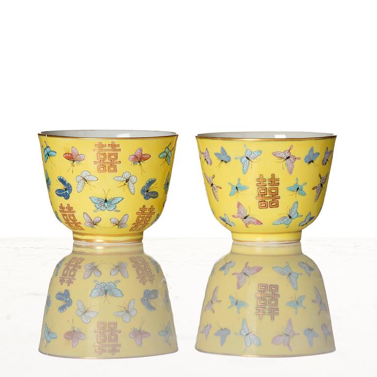 A pair of yellow glazed double happiness cups with butterflies, Qing dynasty, with Tongzhis four character mark to base.