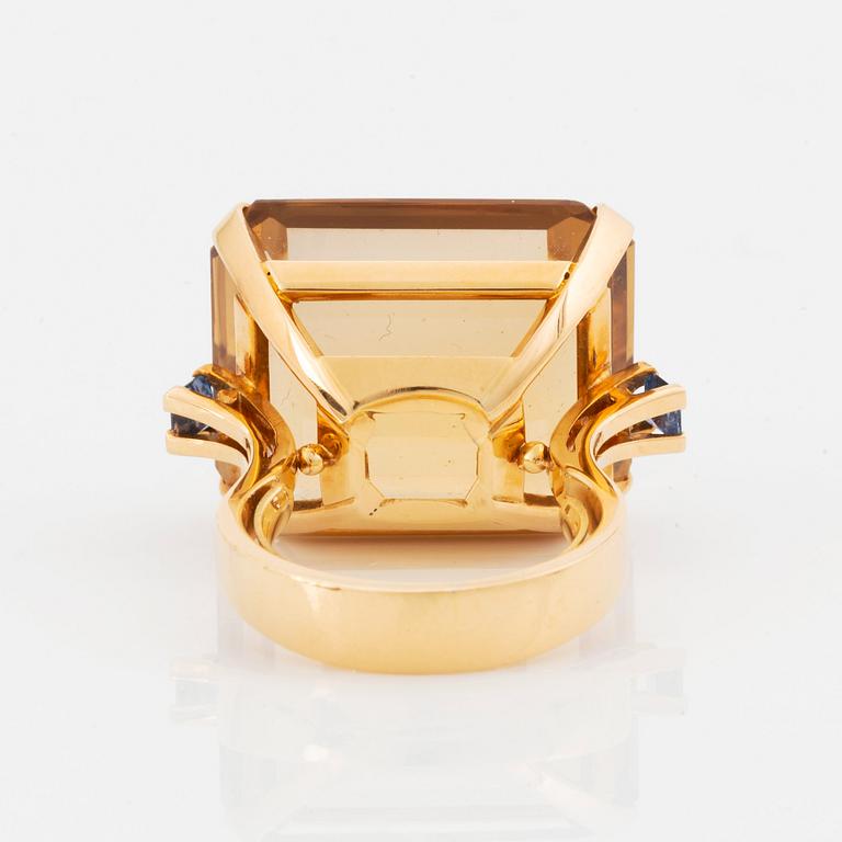 An 18K gold ring set with a faceted citrine and two sapphires.