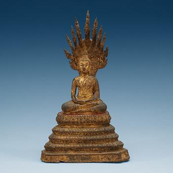 1865. A gilt bronze figure of Buddha, enthroned on a seven headed coiled Naga, Thailand, 19th Century.