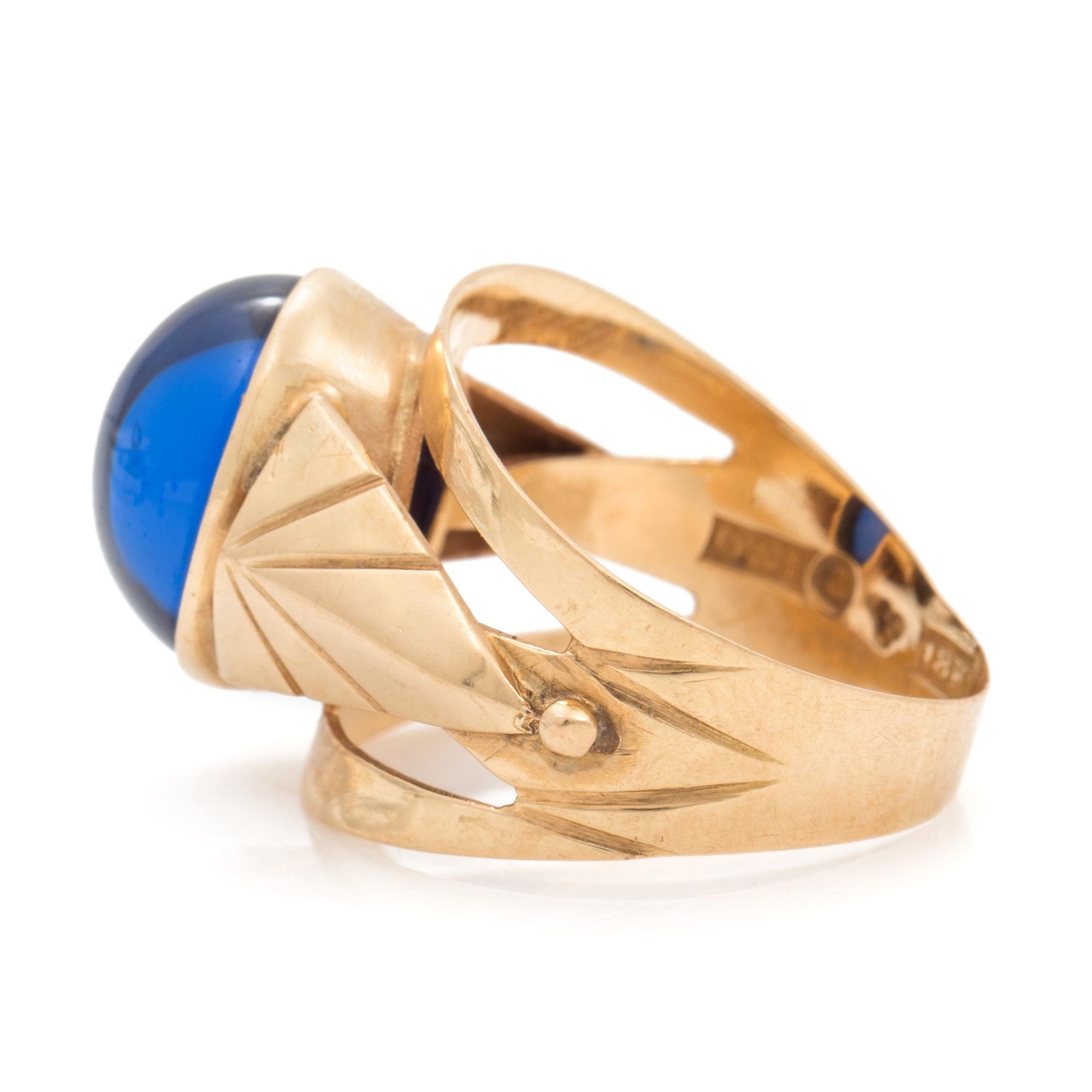 A ring set with an oval, cabochon-cut, synthetic, blue spinel.