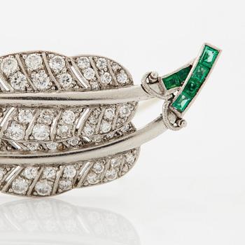 A platinum brooch set with round brilliant-cut diamonds and emeralds.
