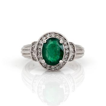 A ring with an oval, mixed-cut emerald and diamonds.