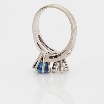 A CROSS-OVER RING set with a round mixed-cut sapphire and round brilliant-cut diamonds.