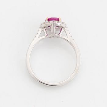 An 18K white gold ring set with a faceted pink sapphire and round brilliant-cut diamonds.