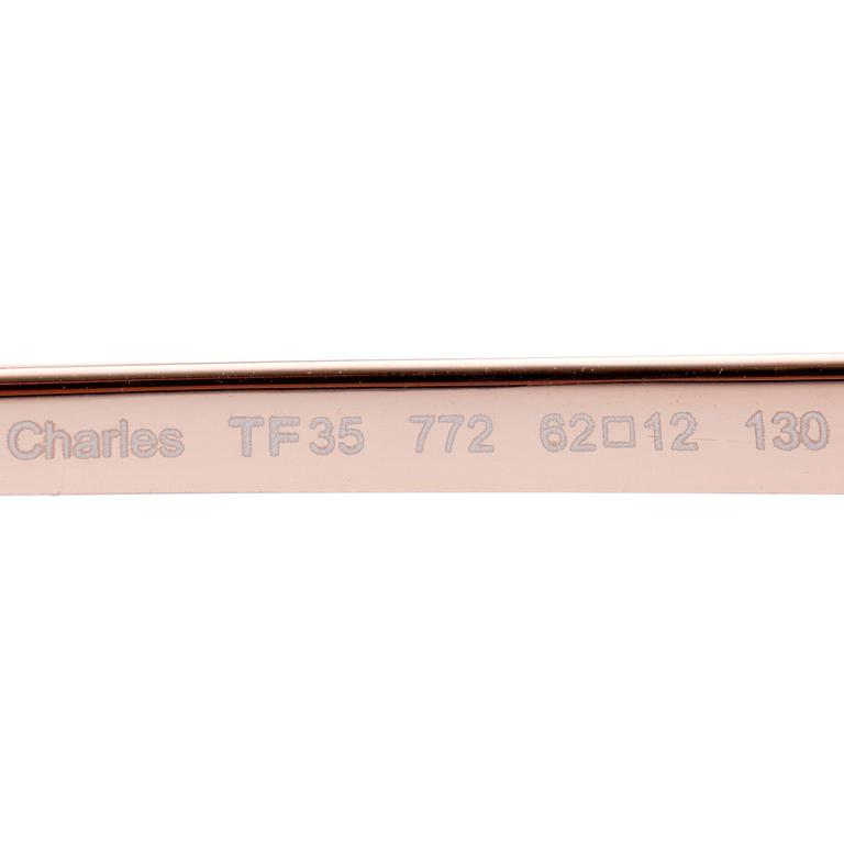 TOM FORD, a pair of gold colored sunglasses.