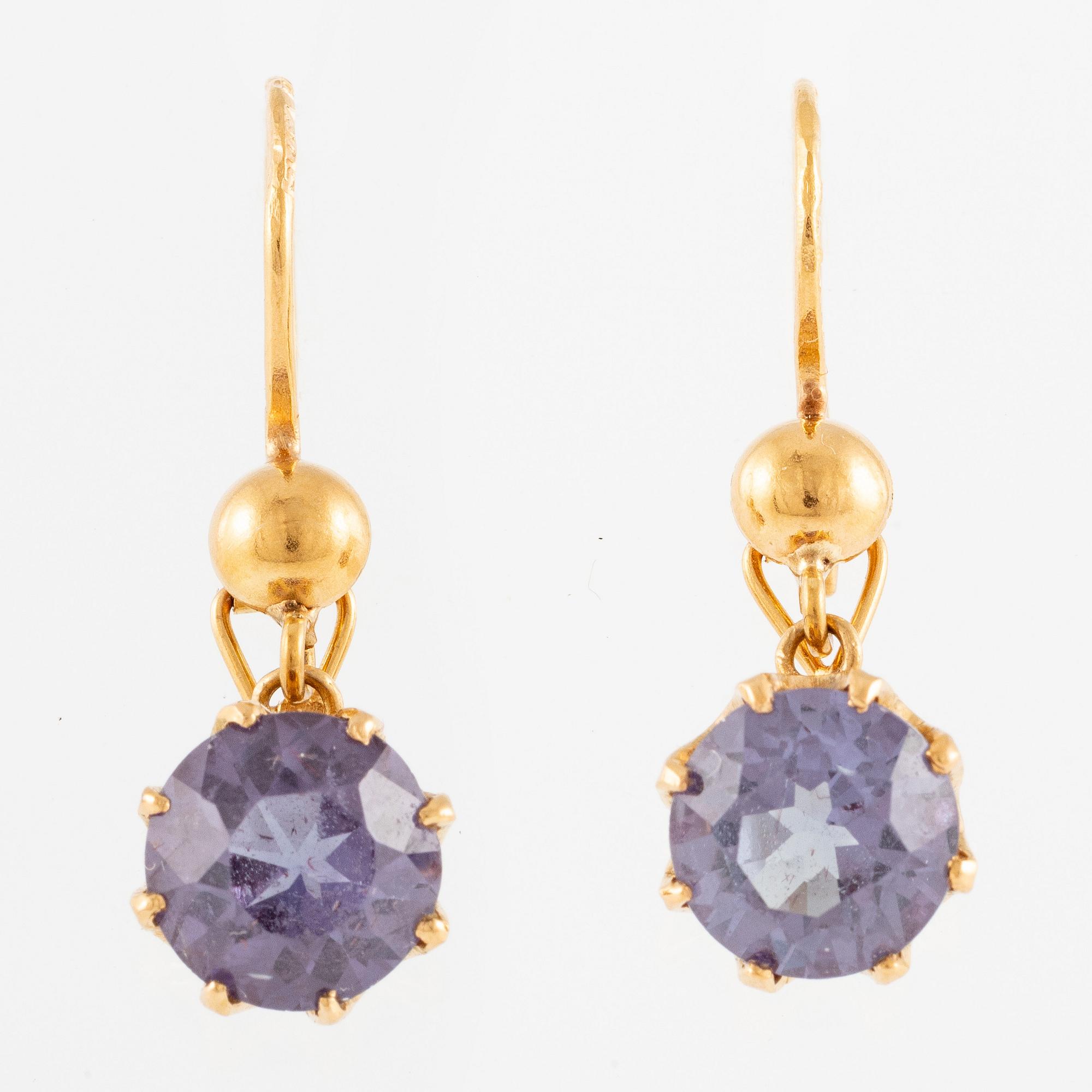 A pair of earrings in 18K gold with purple stones.