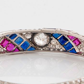 A platinum bangle set with old- and rose-cut diamonds and faceted sapphires and rubies.