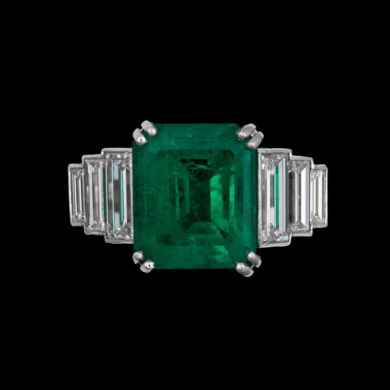 A step cut emerald app 6 cts, flanked by diamonds.