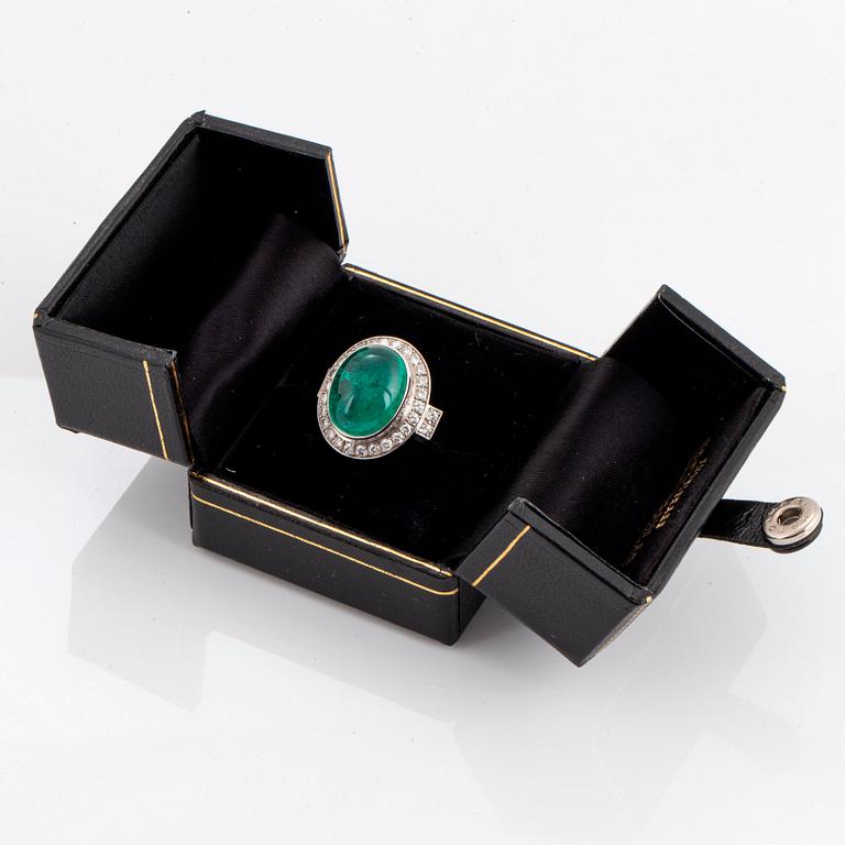 An 18K white gold ring set with a cabochon-cut emerald and round brilliant-cut diamonds.