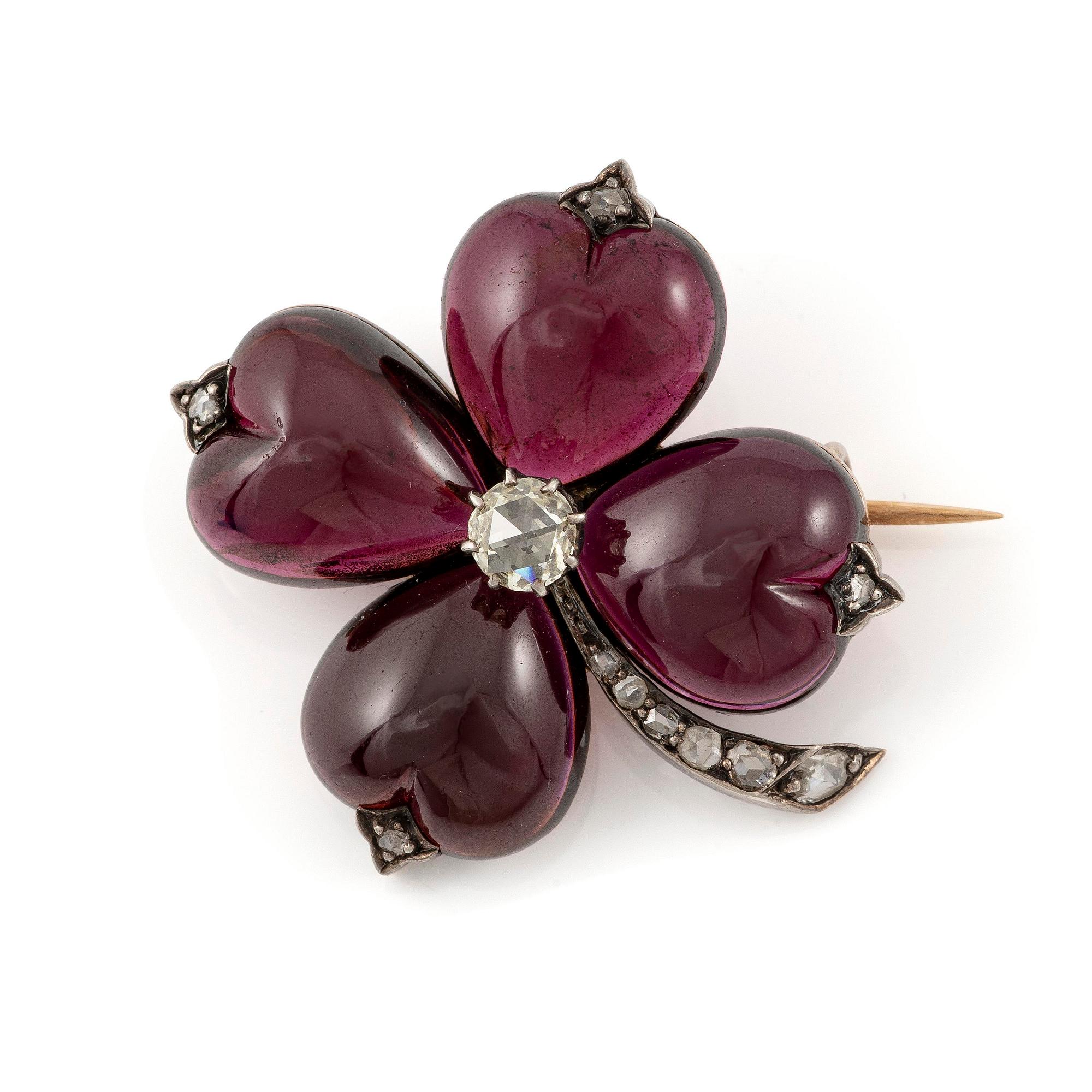 A brooch in the shape of a four-leaf clover, gold and silver with garnets and rose-cut diamonds.