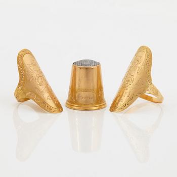 An 18K gold sew set comprising two rings and one thimble.