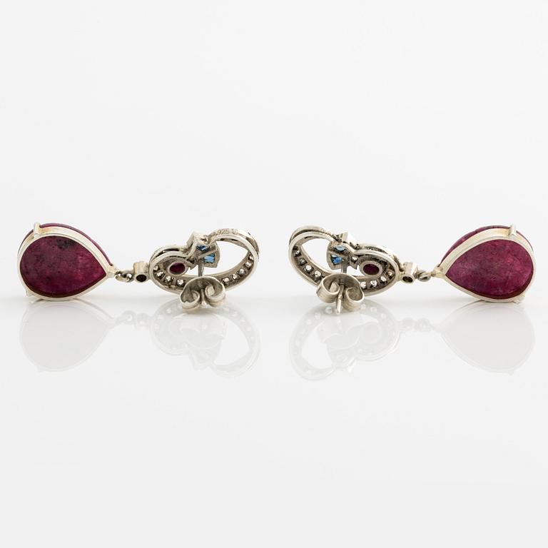 Silver earrings with carved rubies featuring floral motifs, sapphires, and rose-cut diamonds.