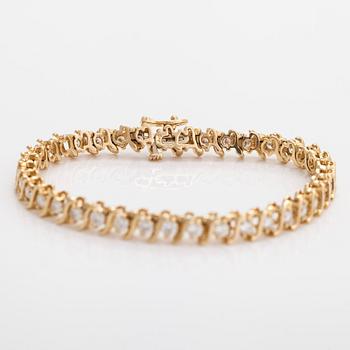 A 14K gold tennis bracelet, with brilliant-cut diamonds.