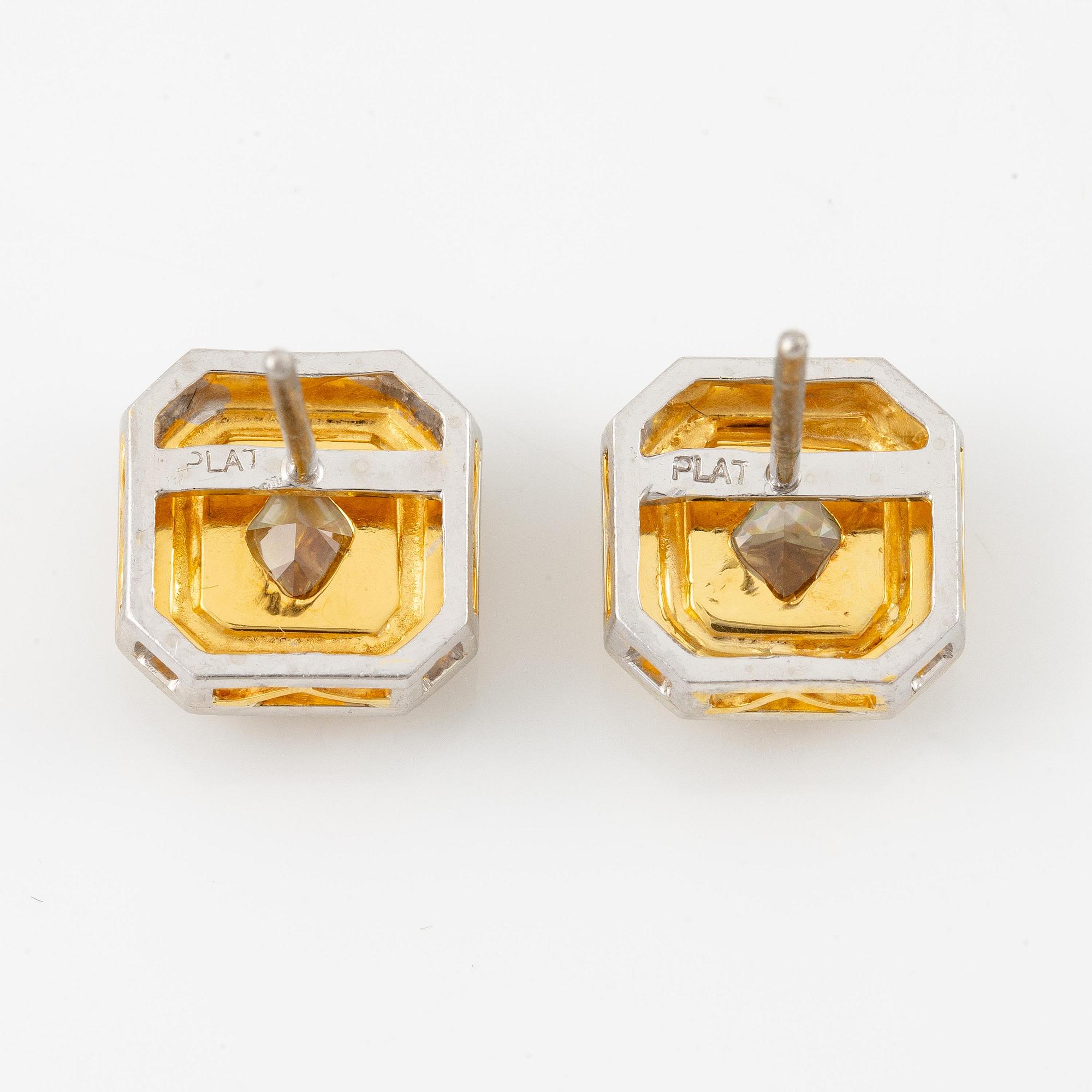 A pair of platinum and gold earrings with two radiant-cut yellow diamonds.