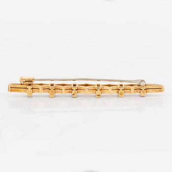 An 18K gold brooch set with step-cut emeralds and round brilliant-cut diamonds.
