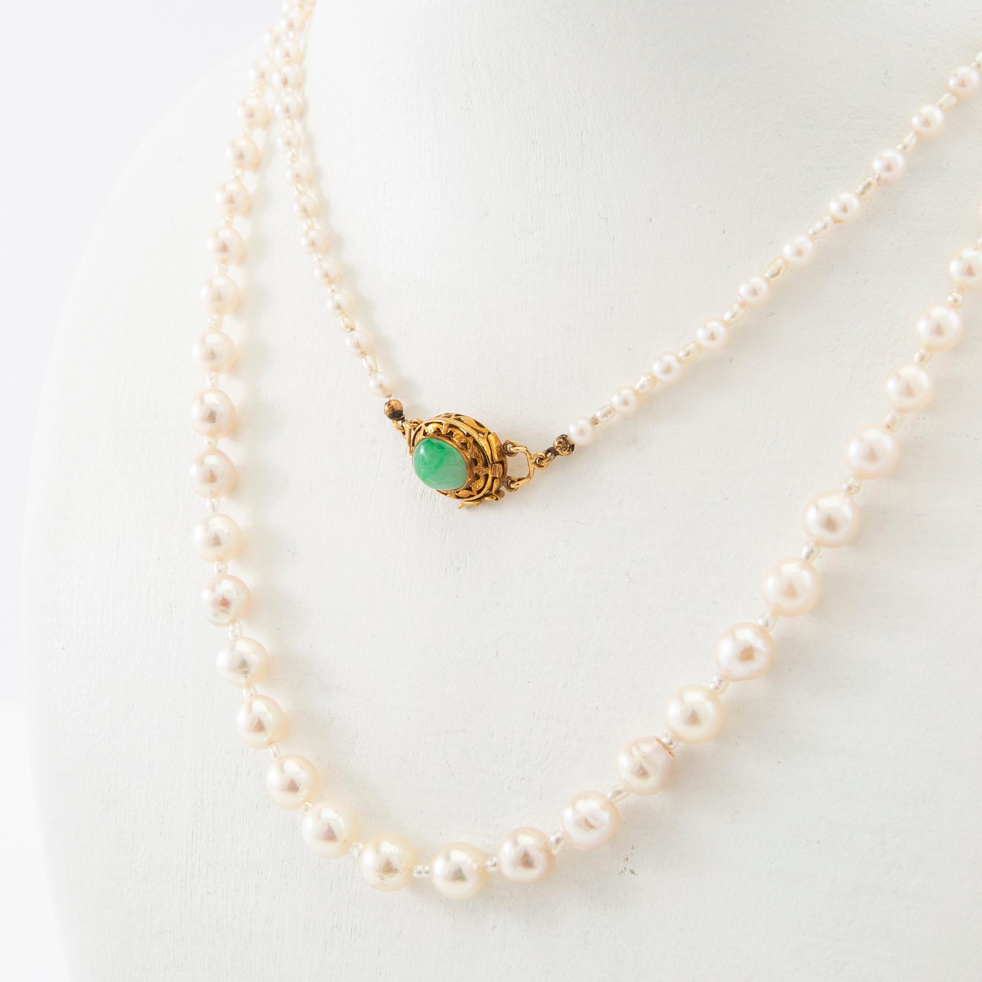 Necklace of cultured pearls with a clasp of 18K gold and cabochon-cut green stone.